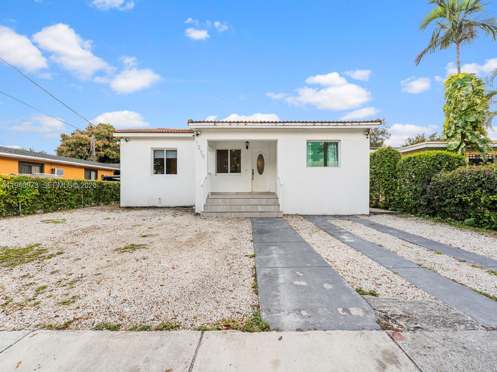 A single-story white house features a gravel front yard and a concrete driveway — 1230 NW 35th St, Miami FL 33142, MIAMI, FL
