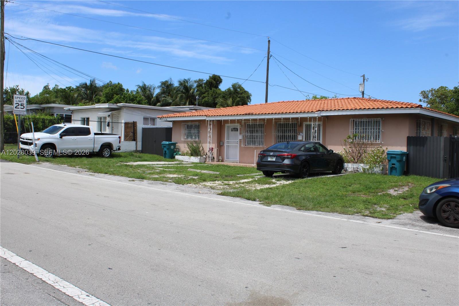 A single-story house with a terracotta tile roof and a front yard with parked cars — 1040 NW 23rd Ct, Miami FL 33125, MIAMI, FL