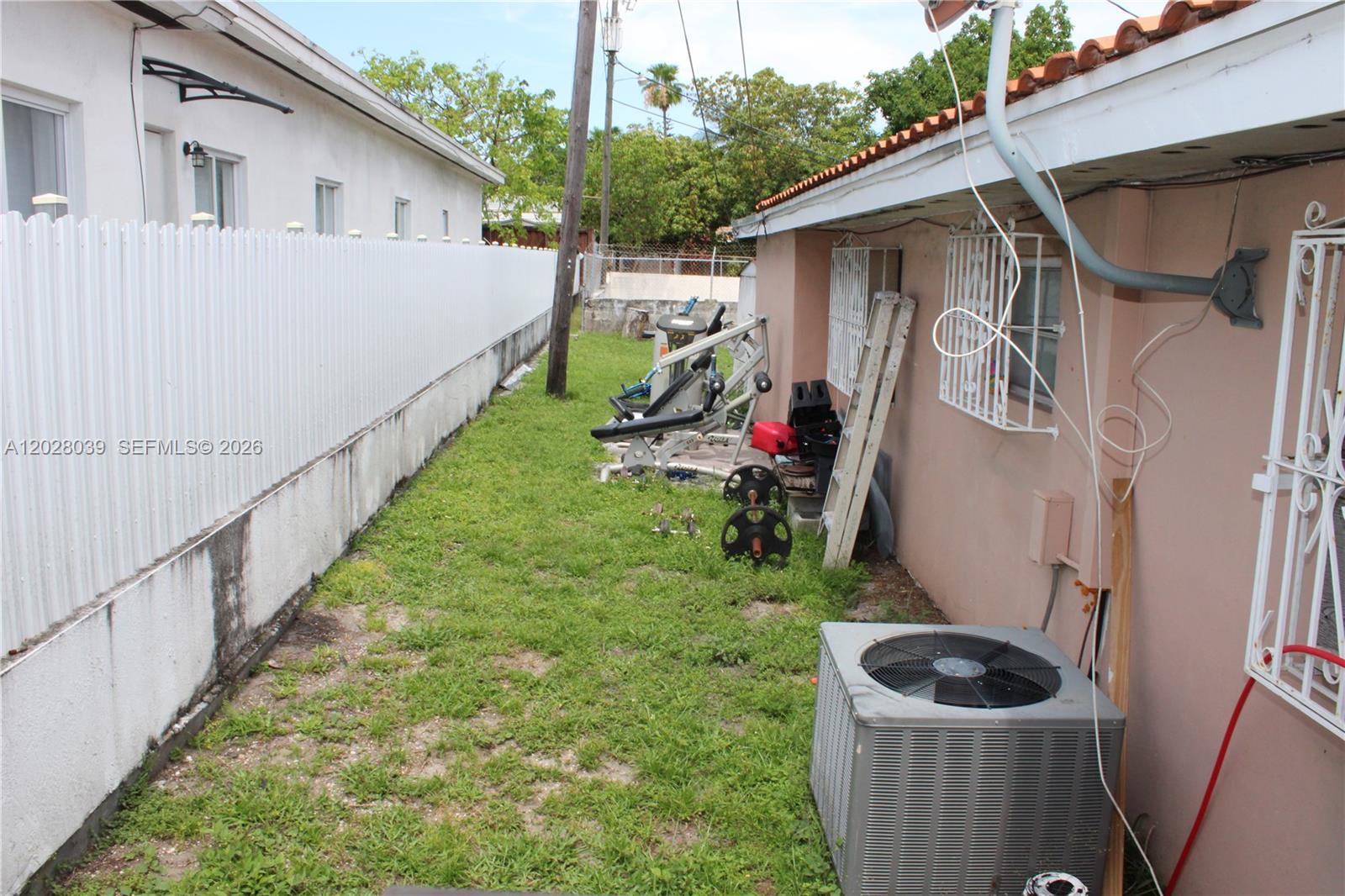 A narrow side yard features a grass lawn, exercise equipment, and an air conditioning unit — 1040 NW 23rd Ct, Miami FL 33125, MIAMI, FL