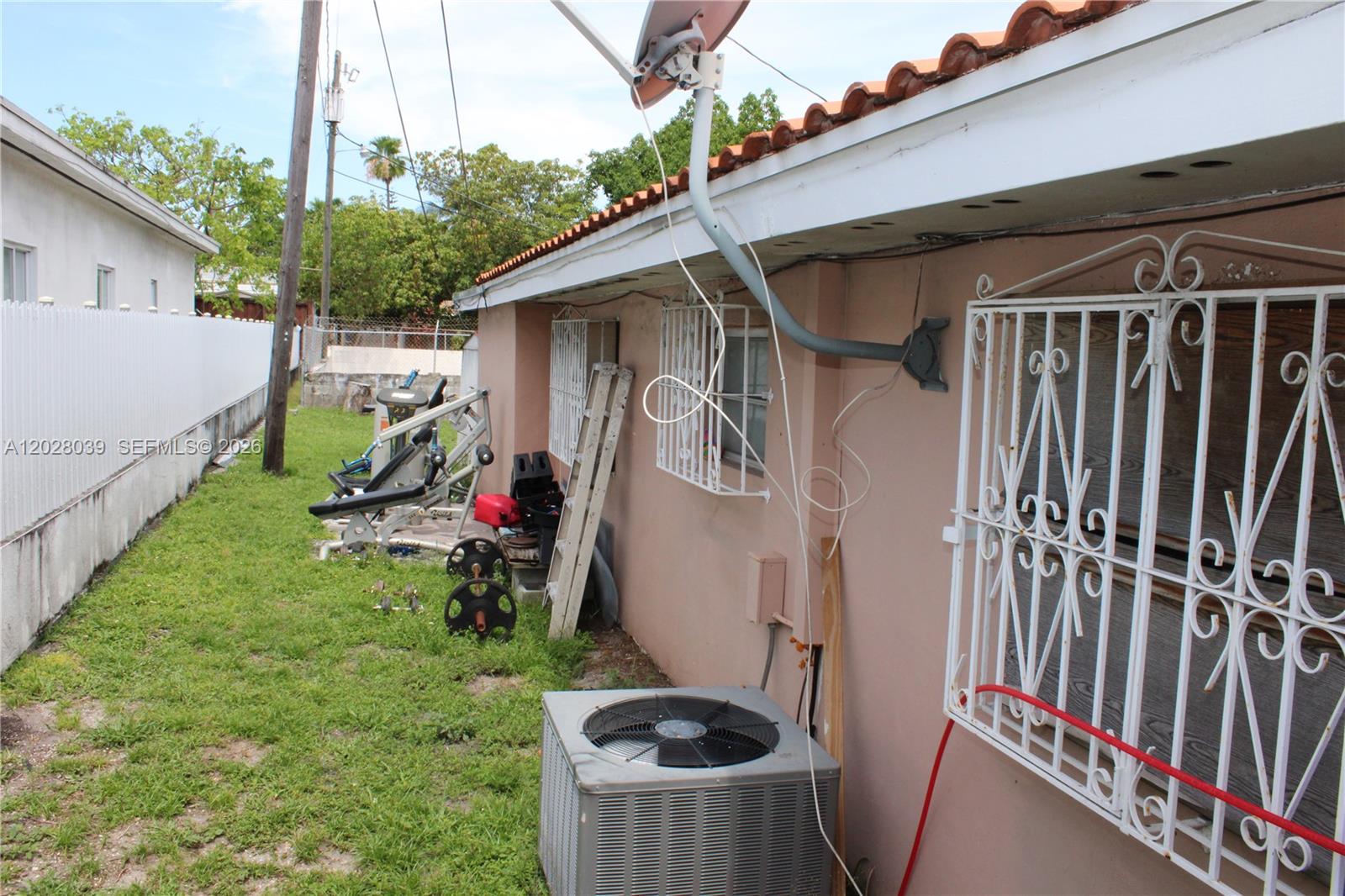 The exterior side of a house features a satellite dish, air conditioning unit, and gym equipment — 1040 NW 23rd Ct, Miami FL 33125, MIAMI, FL