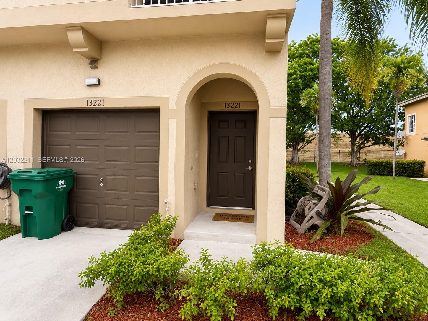 The exterior of a tan townhouse features a brown garage door and a matching front door — 13221 SW 42nd St # 8203, Miramar FL 33027, MIRAMAR, FL