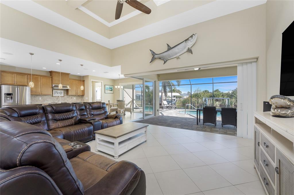 A living room with leather furniture, a tray ceiling, and sliding doors opening to a pool — 9386 ARRID CIRCLE, PORT CHARLOTTE, FL
