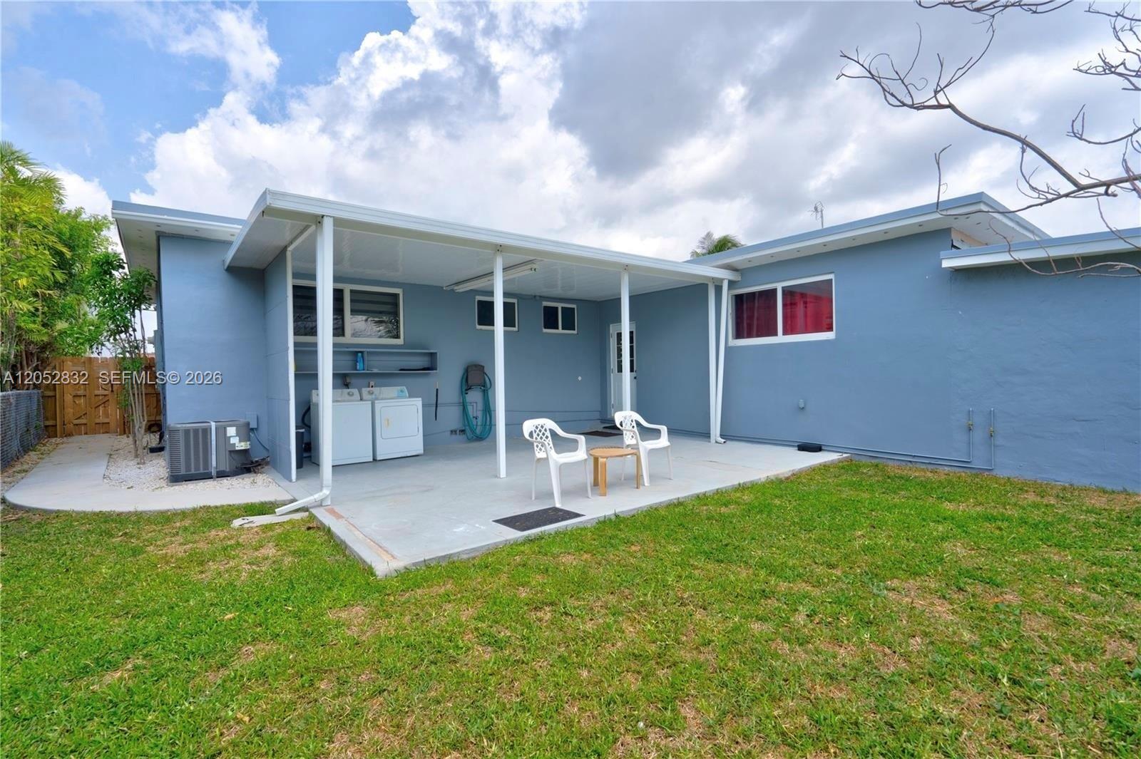 A blue house features a covered concrete patio with a washer and dryer set — 3635 SW 88th Ct, Miami FL 33165, MIAMI, FL