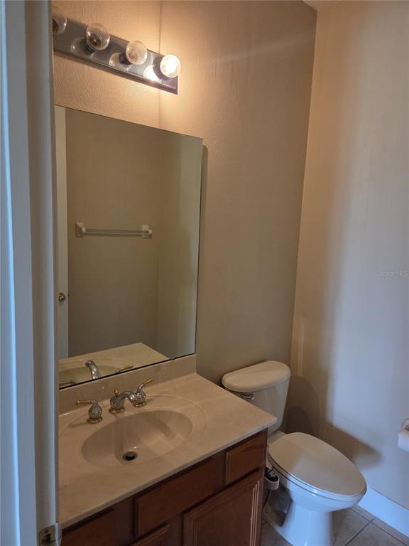 A bathroom features a wooden vanity with a beige countertop, a mirror, and a toilet — 2770 BOAT COVE CIRCLE, KISSIMMEE, FL