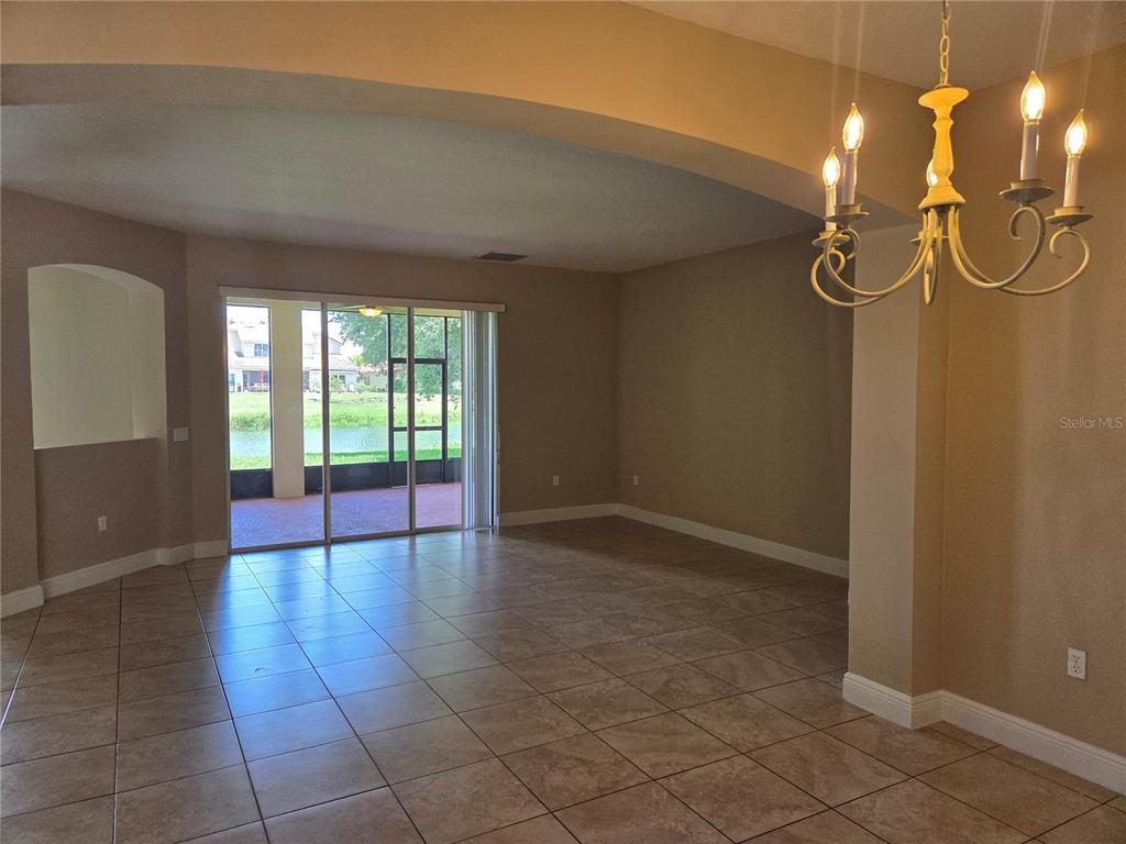 A tiled living area features an arched ceiling, a chandelier, and sliding doors to a patio — 2770 BOAT COVE CIRCLE, KISSIMMEE, FL