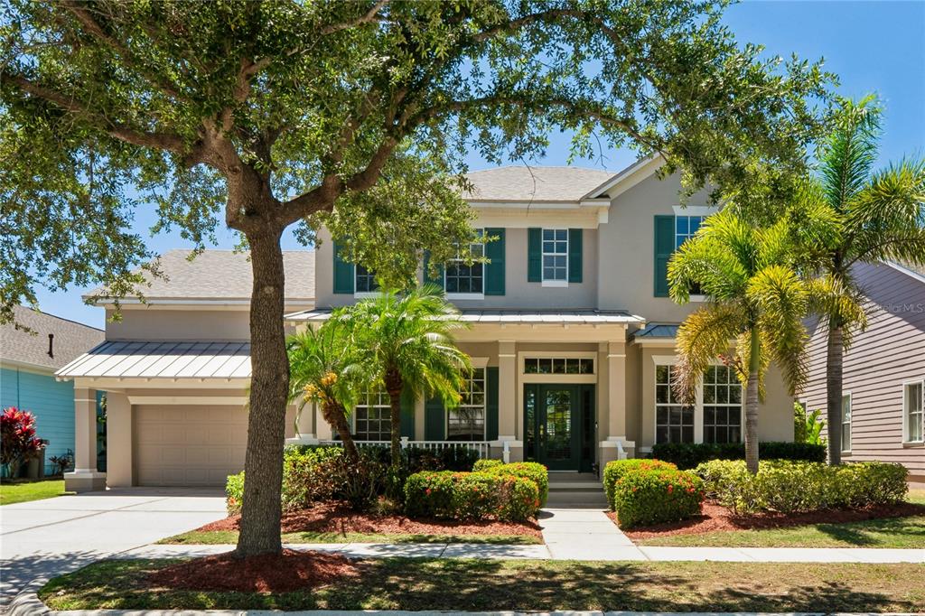 A two-story house with a tan exterior, green shutters, a front porch, and palm trees — 5714 SEA TROUT PLACE, APOLLO BEACH, FL