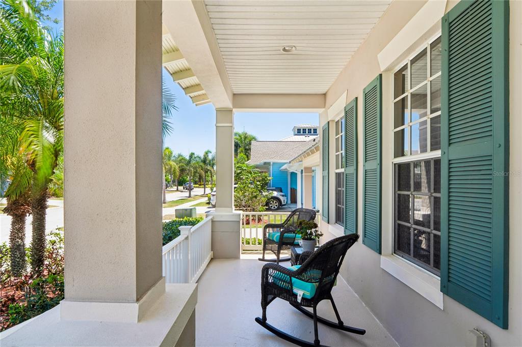 A covered front porch features two rocking chairs, white railings, and green window shutters — 5714 SEA TROUT PLACE, APOLLO BEACH, FL