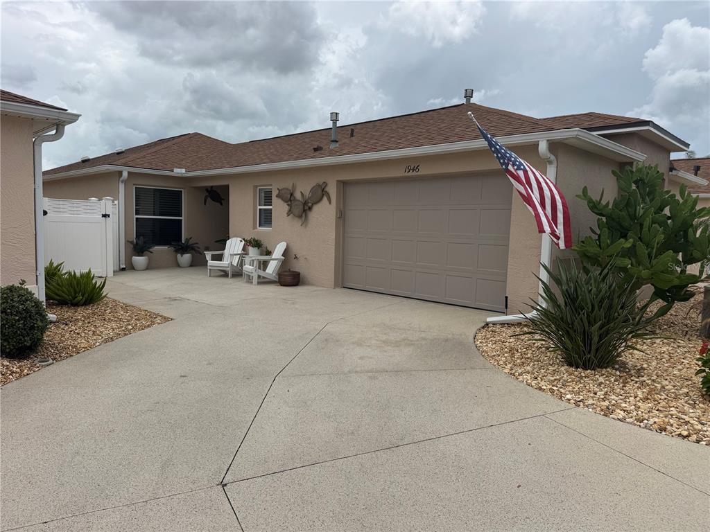 A tan single-story house with a garage, a concrete driveway, and an American flag — 1946 MCCONNELLS AVENUE, THE VILLAGES, FL