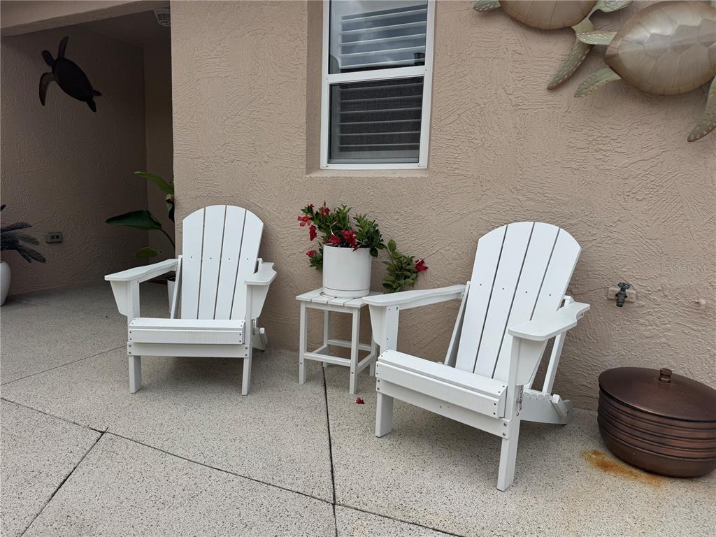 Two white Adirondack chairs and a small table with a plant sit on a patio — 1946 MCCONNELLS AVENUE, THE VILLAGES, FL