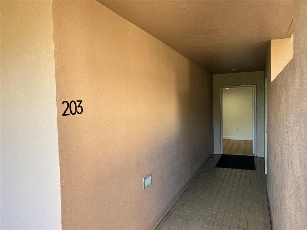 A hallway leads to an open doorway, featuring a numbered wall and tiled flooring — 6260 KIPPS COLONY COURT UNIT 203, GULFPORT, FL