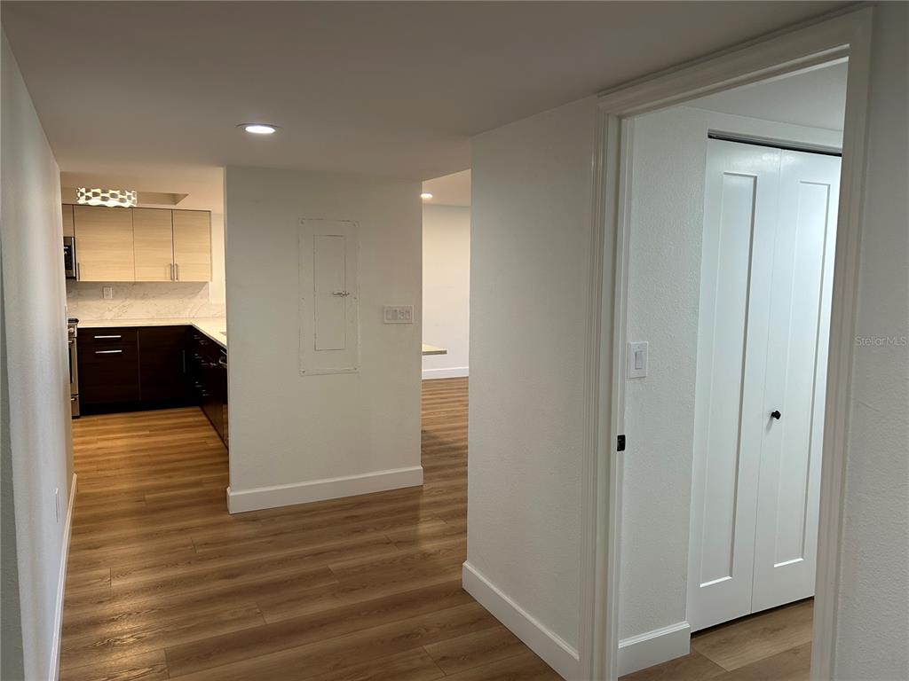 A view from a hallway looking into a kitchen with wood-look flooring and white walls — 6260 KIPPS COLONY COURT UNIT 203, GULFPORT, FL
