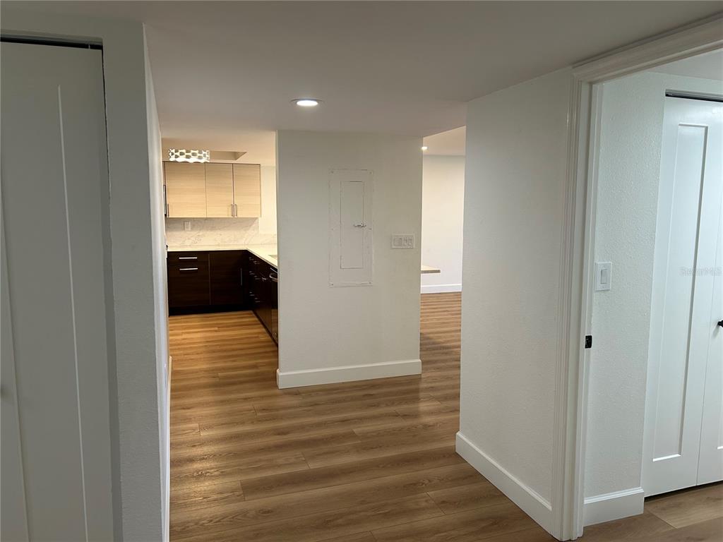 A hallway with wood-look flooring leads to a kitchen with two-toned cabinets — 6260 KIPPS COLONY COURT UNIT 203, GULFPORT, FL