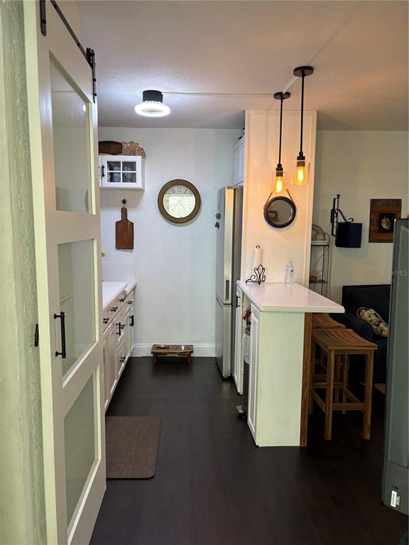 A kitchen features dark wood floors, white cabinetry, a breakfast bar, and a sliding barn door — 935 S ATLANTIC AVENUE UNIT 364, DAYTONA BEACH, FL