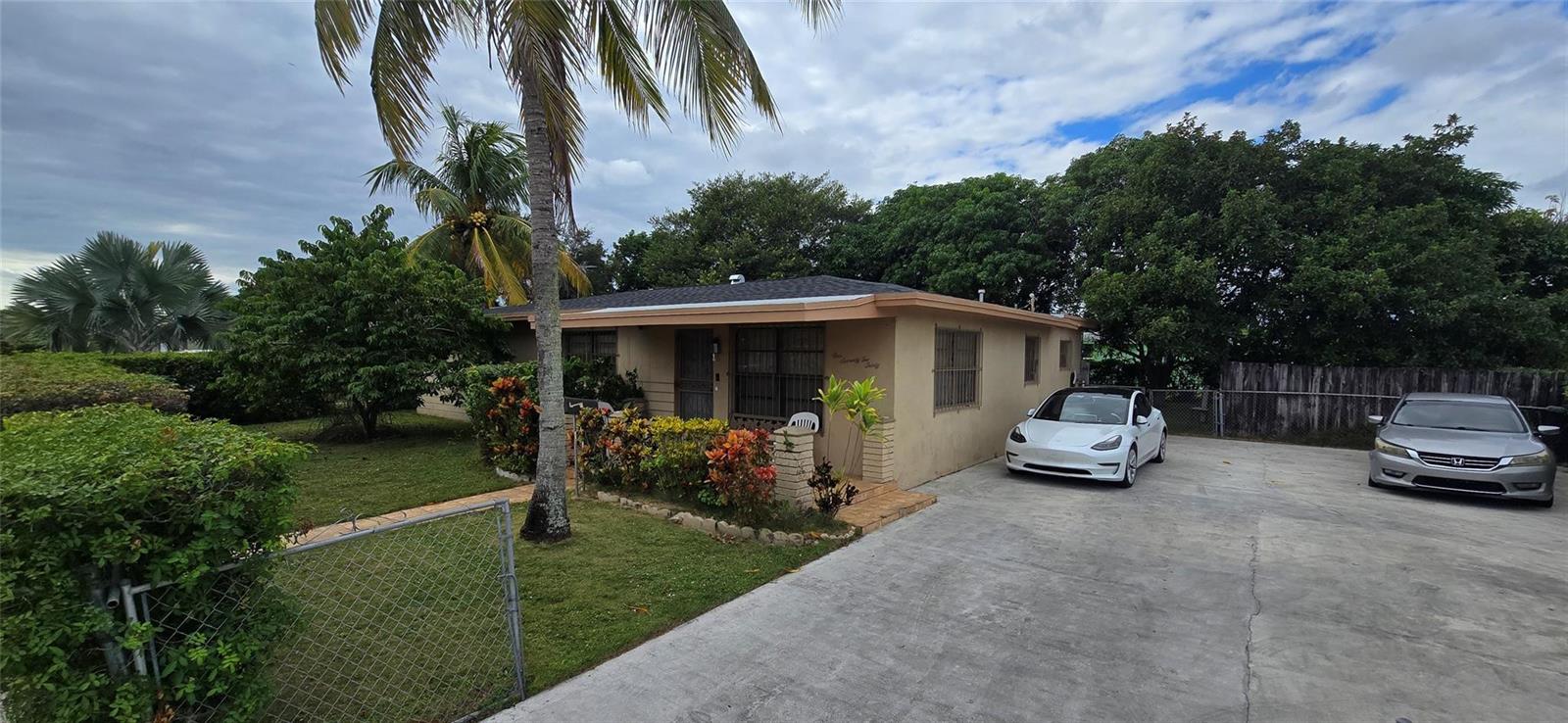 A single-story house with a concrete driveway, two parked cars, and a palm tree — 17230 NW 10th Court, Miami FL 33169, MIAMI, FL