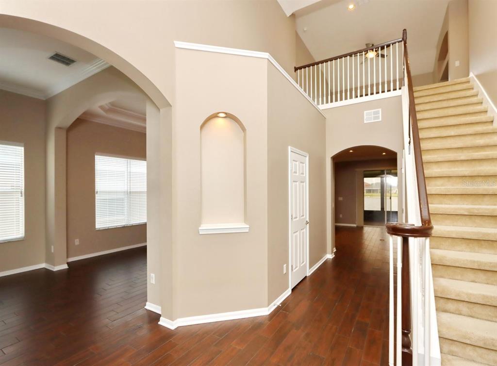 An interior view shows a foyer with hardwood floors, a staircase, and arched wall openings — 13714 ARTESA BELL DRIVE, RIVERVIEW, FL