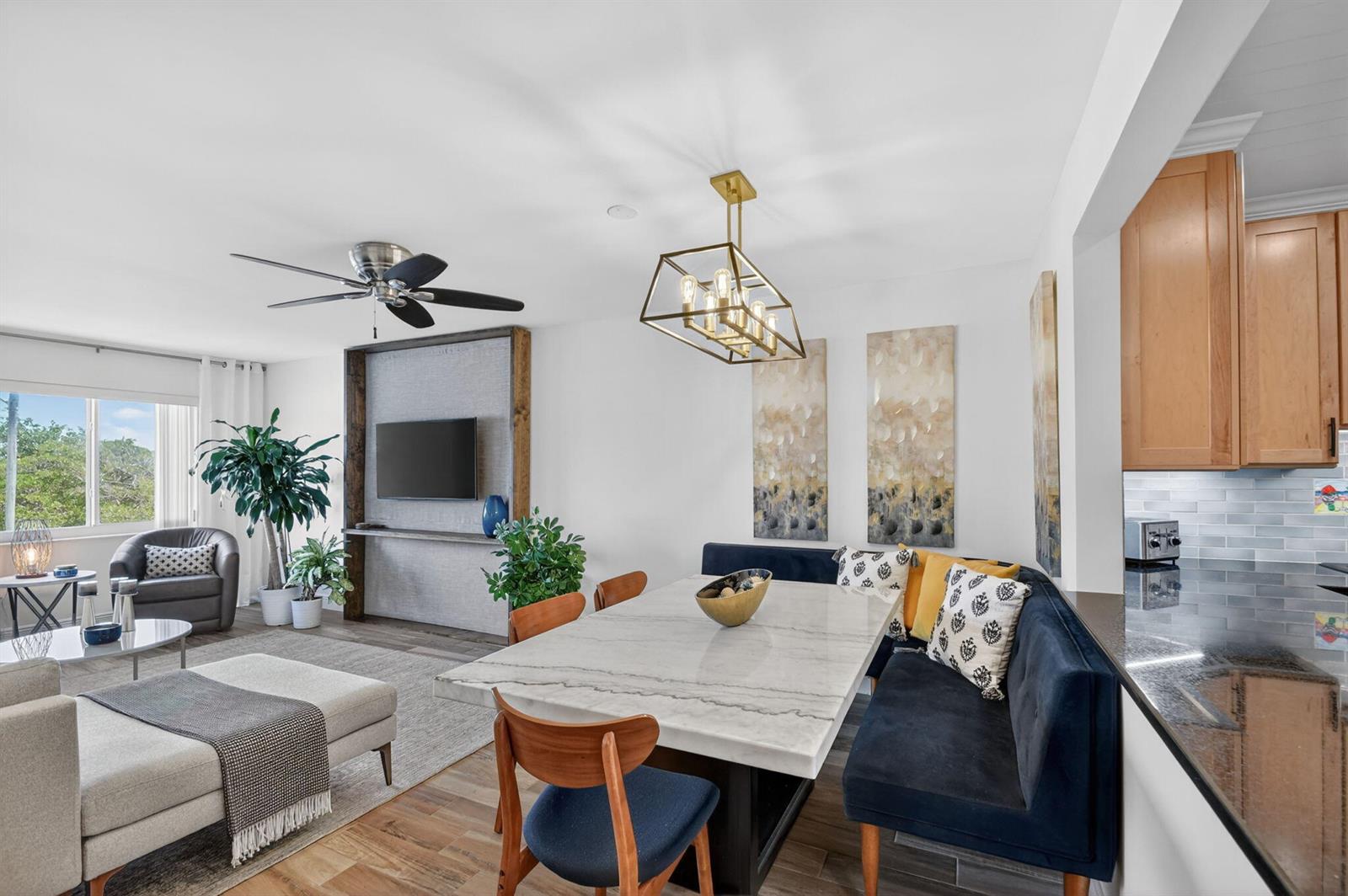 An open-concept living and dining area features a marble-topped table, navy banquette, and television wall — 1502 S Lakeside Drive # 214, FL 33460, FL