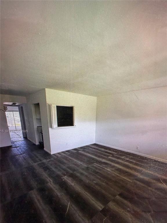 An empty room with dark wood-look flooring, white walls, and a small pass-through window — 42 SHEFFIELD B UNIT B, WEST PALM BEACH, FL