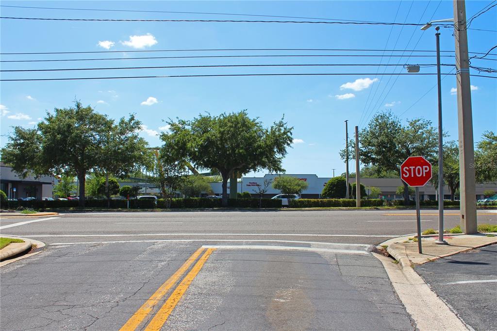 A stop sign stands at the edge of a paved road intersection near a commercial plaza — 2518 S FLORIDA AVENUE, LAKELAND, FL