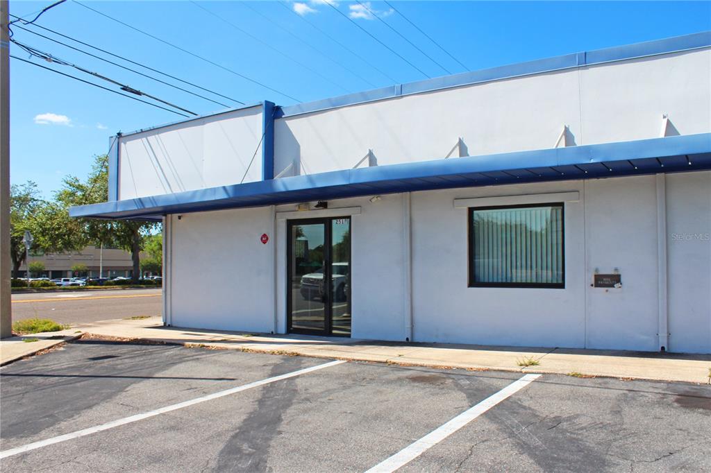 A single-story commercial building with a blue awning, glass entrance door, and asphalt parking lot — 2518 S FLORIDA AVENUE, LAKELAND, FL