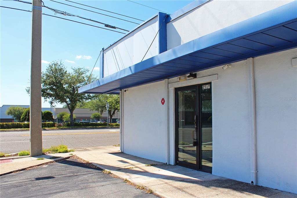 A white commercial building exterior features a blue awning and a glass entry door — 2518 S FLORIDA AVENUE, LAKELAND, FL
