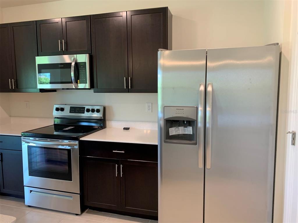 A kitchen featuring dark wood cabinets, stainless steel appliances, and white countertops — 341 TANDIL STREET, PUNTA GORDA, FL
