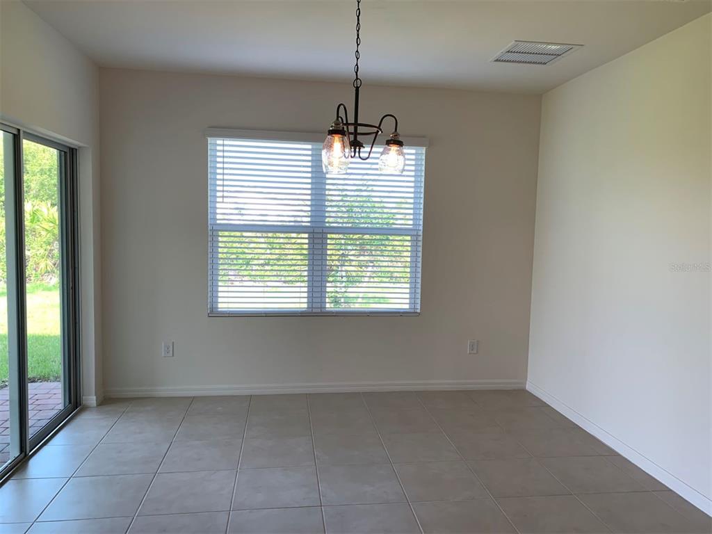 An empty dining area features tile flooring, a hanging light fixture, and sliding glass doors — 341 TANDIL STREET, PUNTA GORDA, FL