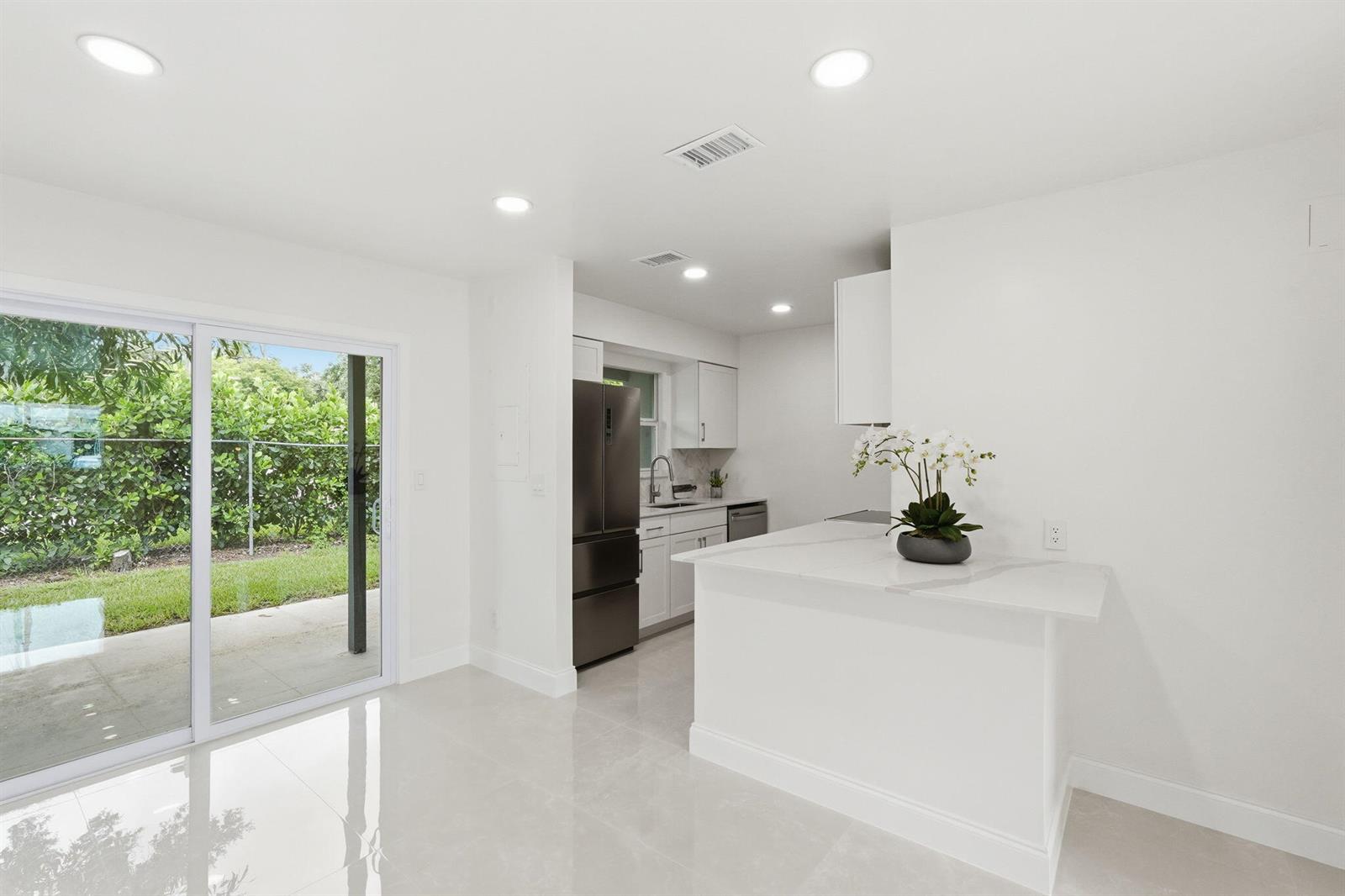 A bright kitchen features white cabinets, stainless steel appliances, and a sliding glass door — 6505 Dockside Circle, FL 33463, FL