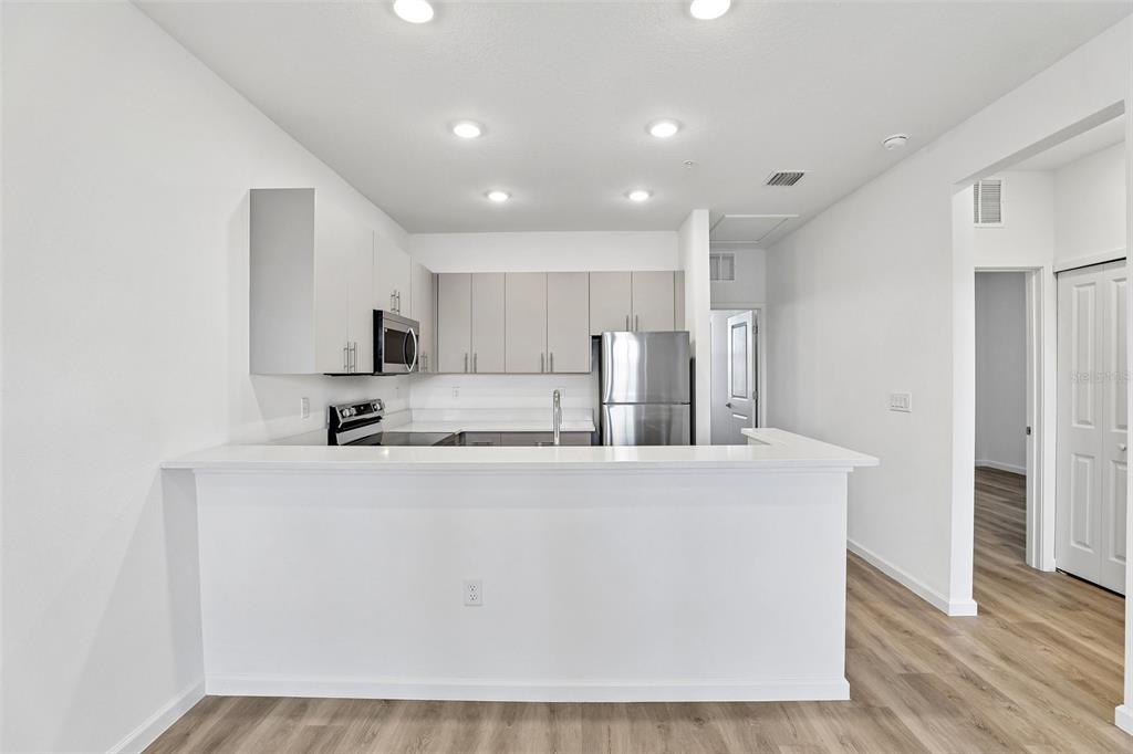 A kitchen features light-colored cabinets, stainless steel appliances, and a white breakfast bar — 3065 SOLDIER CITY WAY UNIT 201, ST CLOUD, FL