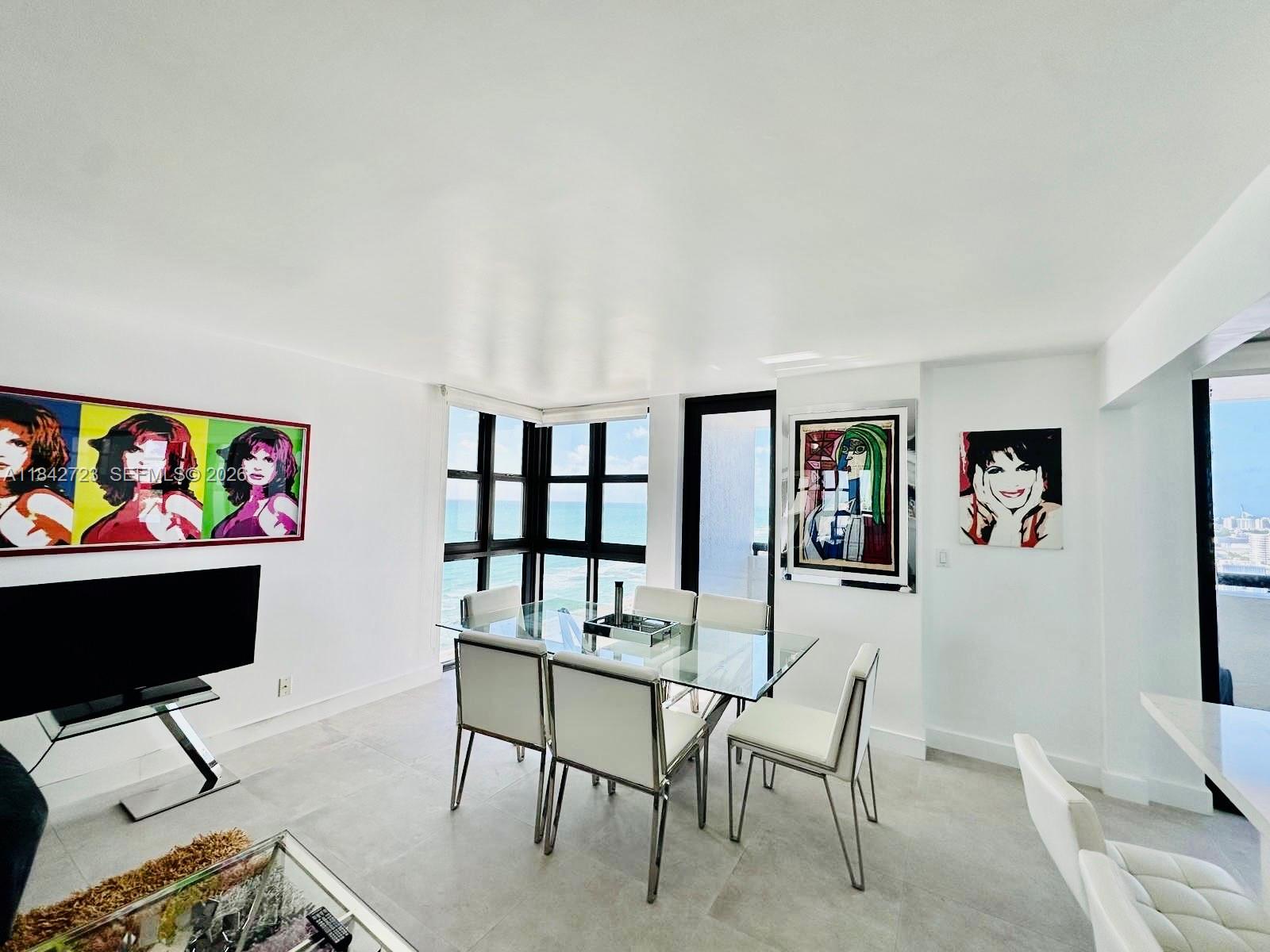 A living and dining area features a sectional sofa, glass tables, and ocean views — 2555 Collins Ave, Miami Beach FL 33140, MIAMI BEACH, FL