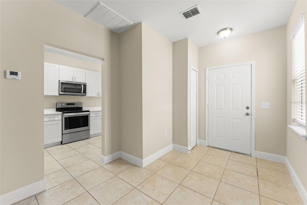 A tiled dining area leads into a kitchen with white cabinets and stainless steel appliances — 498 DEAN CREEK LANE, ORLANDO, FL