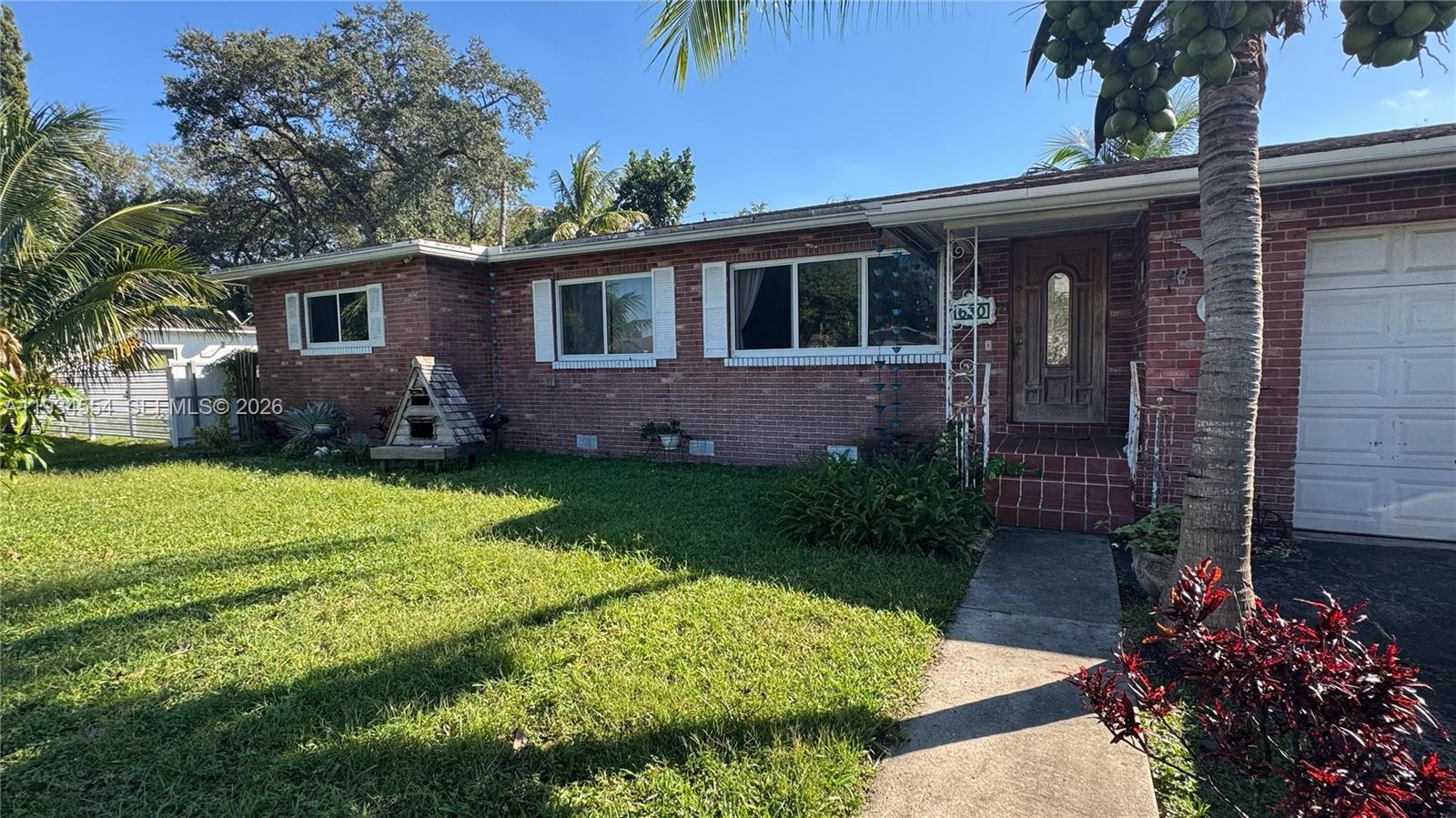 A single-story brick house features a front lawn, a concrete walkway, and a palm tree — 630 NE 165th St, Miami FL 33162, MIAMI, FL