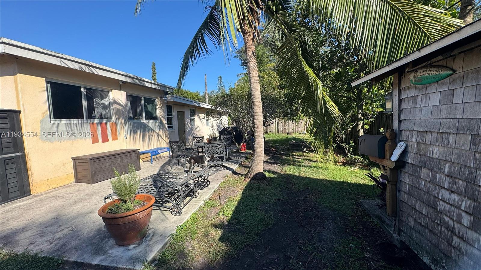 A backyard patio features a palm tree, outdoor furniture, and a small wooden shed — 630 NE 165th St, Miami FL 33162, MIAMI, FL