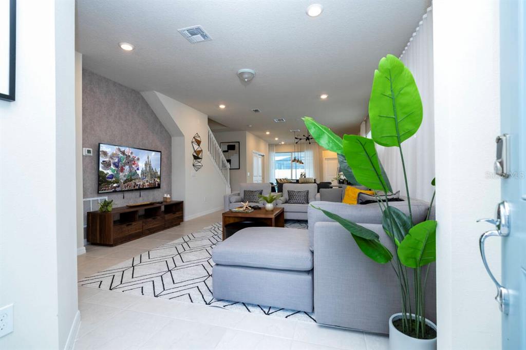 A living room features a grey sectional sofa, a television, and a patterned area rug — 3428 LILAC WAY, DAVENPORT, FL