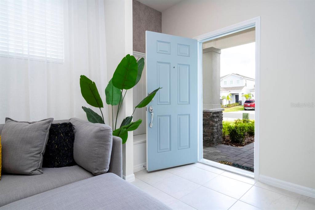 A light blue front door opens from a living room to a suburban street view — 3428 LILAC WAY, DAVENPORT, FL