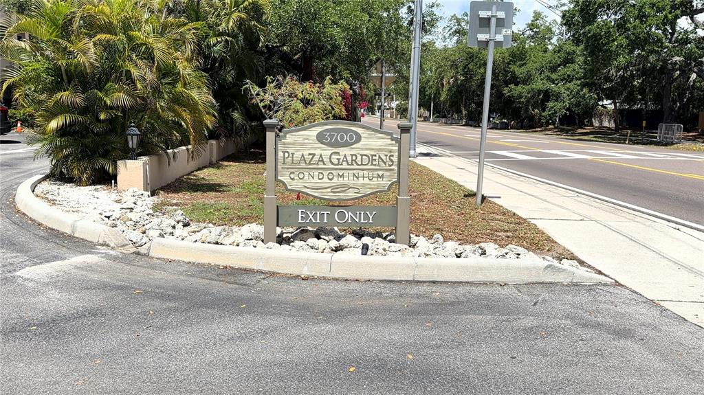 A sign for Plaza Gardens Condominium stands at the exit of a paved driveway — 3700 S OSPREY AVENUE UNIT 205, SARASOTA, FL