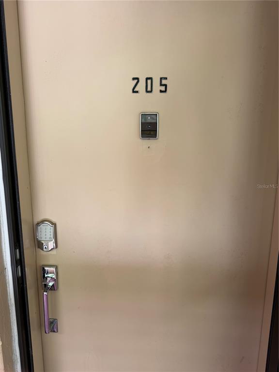 A beige apartment door labeled 205 features a digital keypad lock and a door handle — 3700 S OSPREY AVENUE UNIT 205, SARASOTA, FL