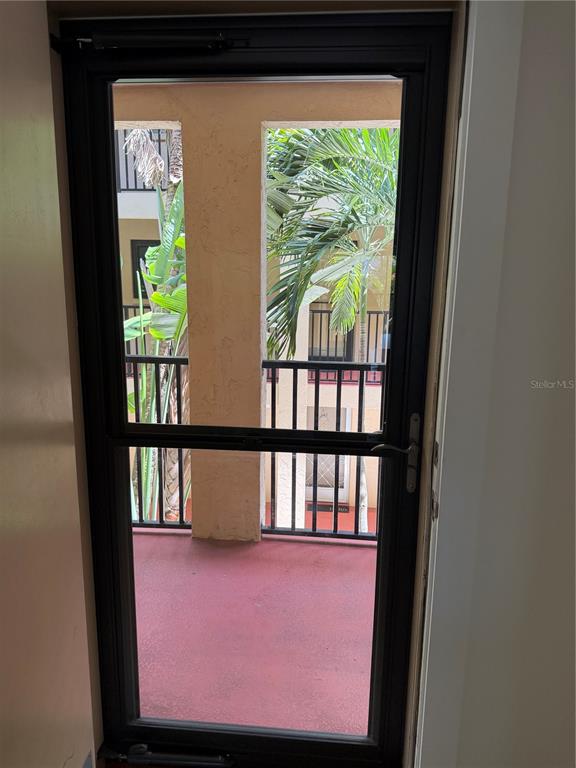 A black-framed storm door opens onto a balcony with a red floor and palm trees — 3700 S OSPREY AVENUE UNIT 205, SARASOTA, FL