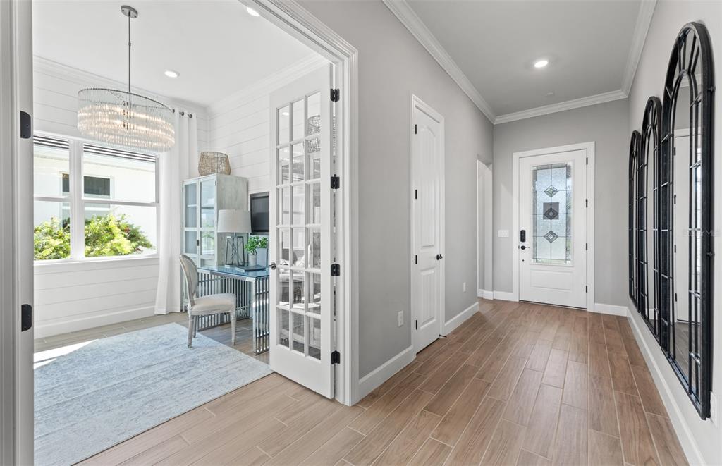 A bright entryway with wood-look tile floors leads to a home office with French doors — 10362 BLUE RUNNER DRIVE, ENGLEWOOD, FL
