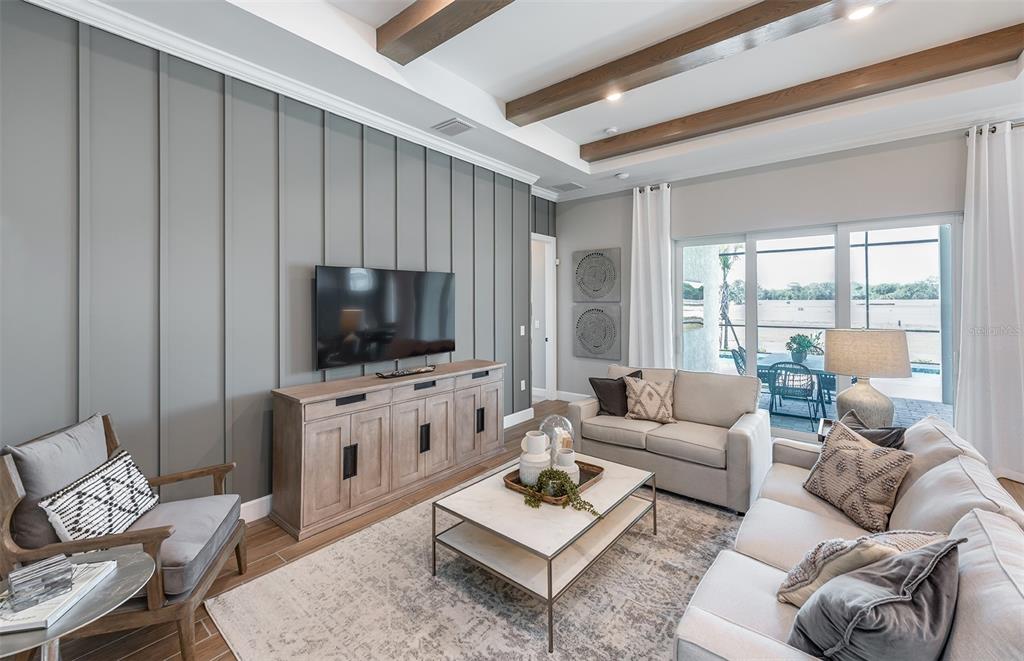 A living room features a gray board-and-batten accent wall, wood ceiling beams, and sliding doors — 10362 BLUE RUNNER DRIVE, ENGLEWOOD, FL
