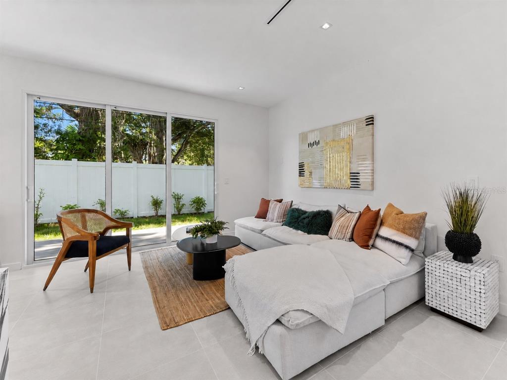 A modern living room features a white sectional sofa, a round coffee table, and sliding doors — 668 NEWTON AVENUE S, ST PETERSBURG, FL