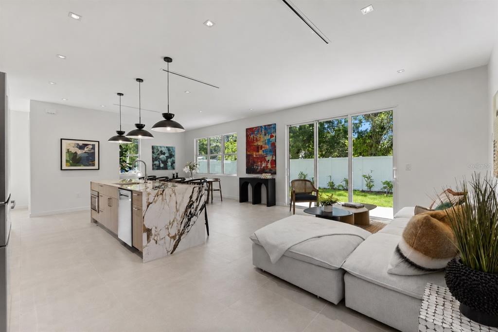 An open-concept kitchen and living area with a marble island, light tile floors, and sliding doors — 668 NEWTON AVENUE S, ST PETERSBURG, FL