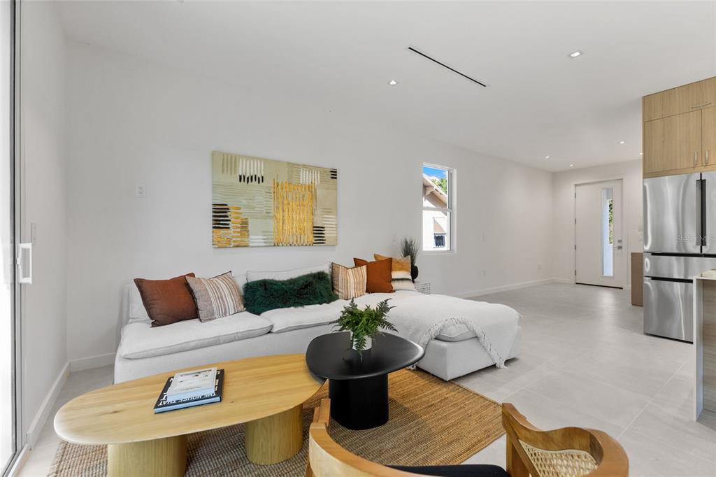 A modern living room features a white sectional sofa, two coffee tables, and neutral tile flooring — 668 NEWTON AVENUE S, ST PETERSBURG, FL