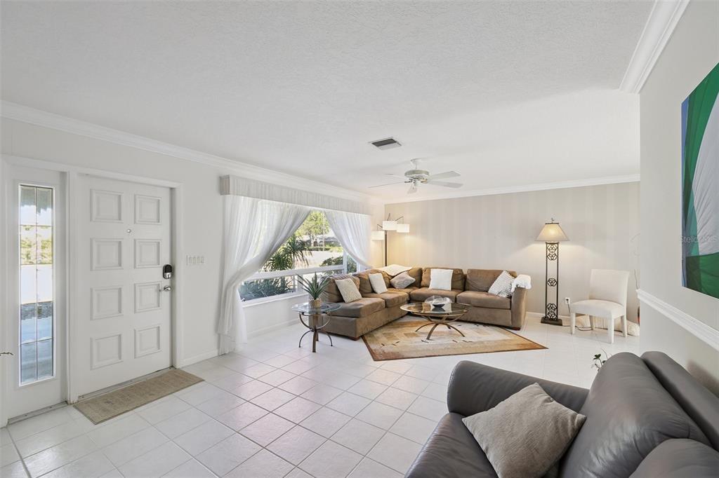 A bright living room features white tile floors, a sectional sofa, and a large window — 325 FIESOLE STREET, VENICE, FL