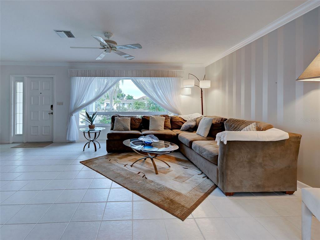 A living room features a brown sectional sofa, a glass coffee table, and striped wallpaper — 325 FIESOLE STREET, VENICE, FL