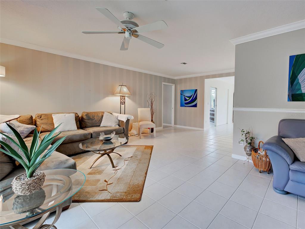 A living room features a brown sectional sofa, a glass coffee table, and tiled flooring — 325 FIESOLE STREET, VENICE, FL