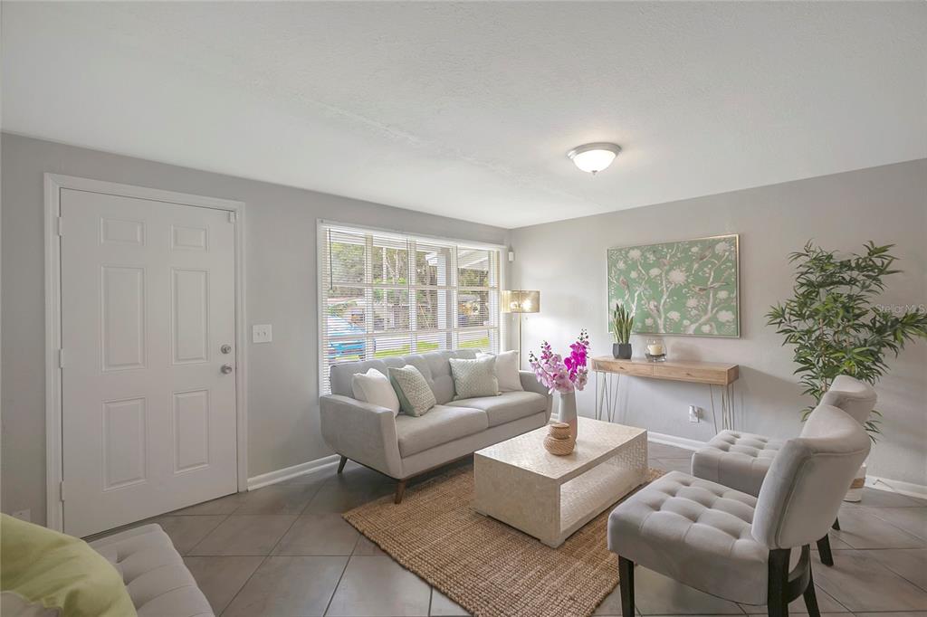 A living room features gray tile floors, a light gray sofa, and two tufted chairs — 3908 E HANNA AVENUE, TAMPA, FL
