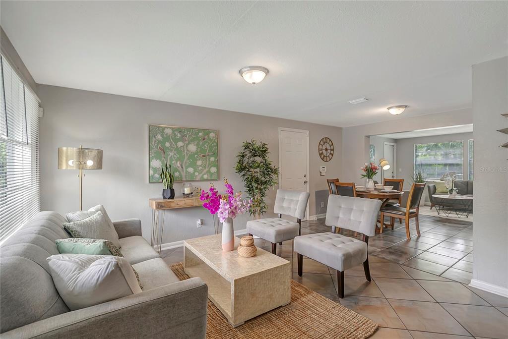 A living room with gray furniture, a stone coffee table, and tile flooring — 3908 E HANNA AVENUE, TAMPA, FL