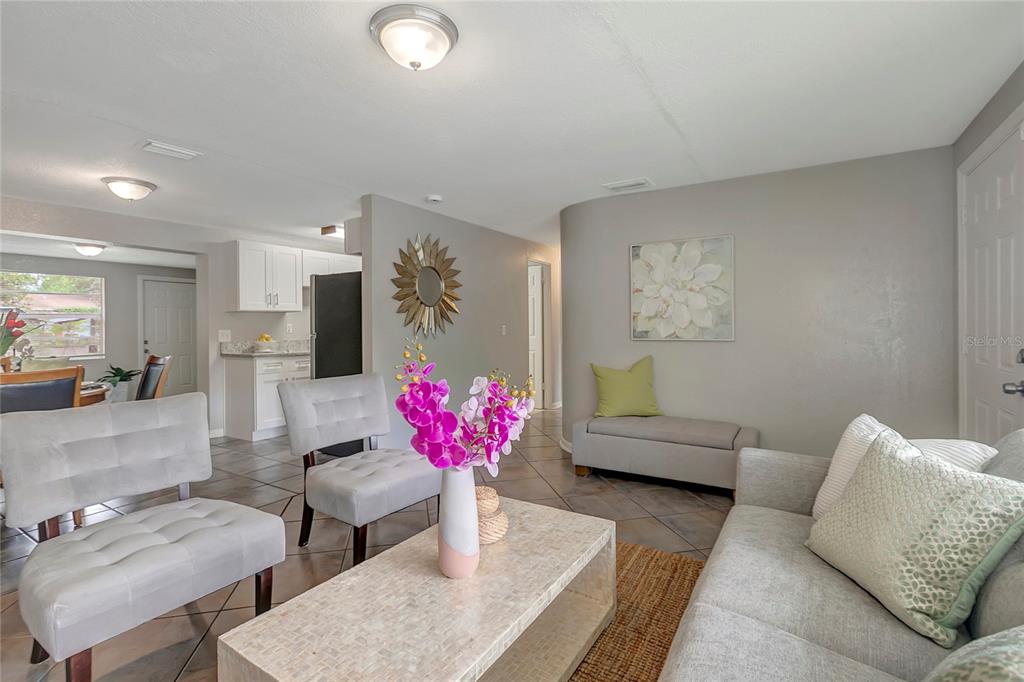 A living room features light gray furniture, a stone coffee table, and tile flooring — 3908 E HANNA AVENUE, TAMPA, FL