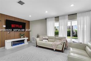 A living room features a wall-mounted television, a fireplace console, and a light-colored sofa — 1540 SE 23rd Ave, Pompano Beach FL 33062, POMPANO BEACH, FL