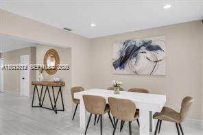 A dining room features a white table, tan chairs, a console table, and abstract wall art — 1540 SE 23rd Ave, Pompano Beach FL 33062, POMPANO BEACH, FL